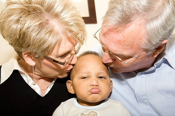 An 87 year old woman giving her 90 year old husband a kiss on the cheek.
