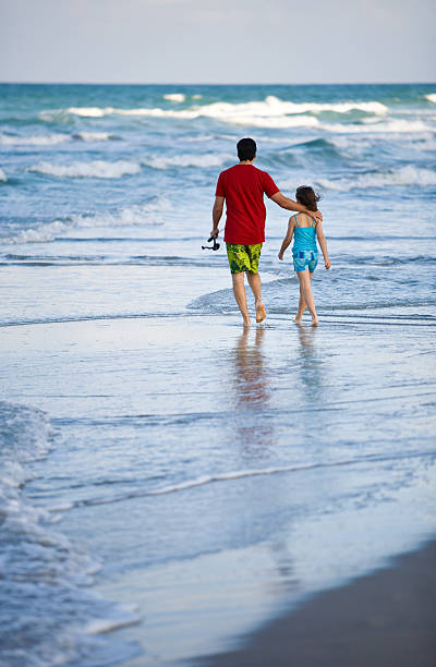 istock Father and daughter walking away on the beach 176136298