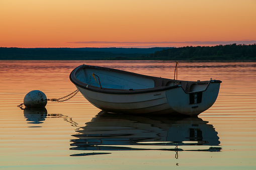 A breathtaking and vivid sunset paints the skies above Lake FinjasjÃ¶n, just outside of HÃ¤ssleholm, Sweden. The serene waters mirror two boats and their captivating reflections.
