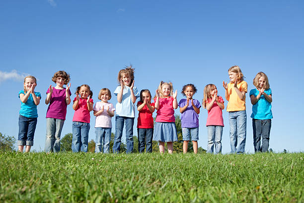 Group of African American children playing and raising their hands in the park. Cheerful diverse black children dancing together outdoor