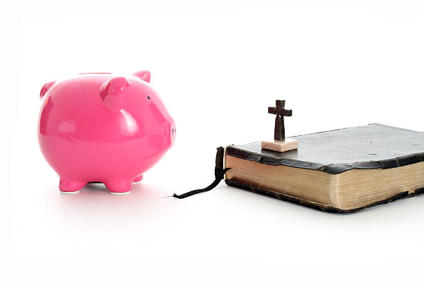 Pink Piggy Bank faces Bible and Cross depicts finances and the Church