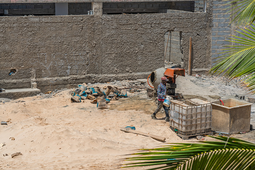 Santa Maria, Sal Island - Cape Verde, October 02.2023: A man in work dress at a concrete mixer make him job