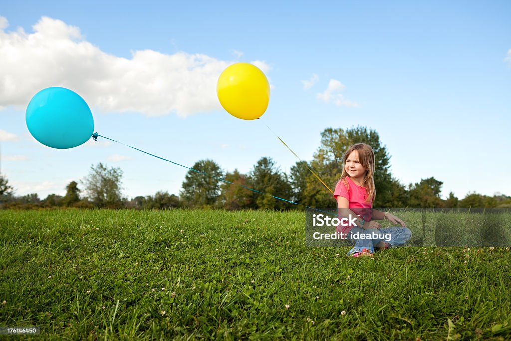 Bambina con palloncini e seduto nell'erba - Foto stock royalty-free di 4-5 anni
