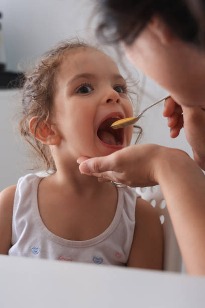 istock Mother feeding little girl with spoon 1761504583
