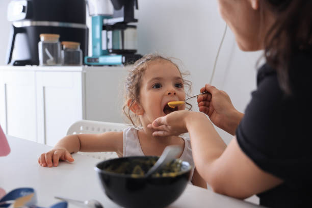 istock Mother feeding little girl with spoon 1761504594