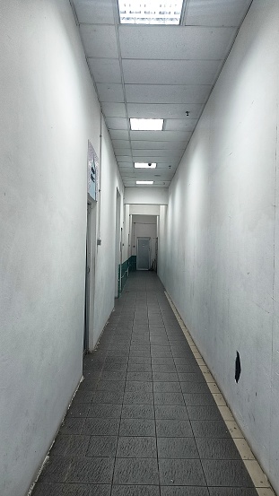 Hallway inside a building with lighting dirty floor and two white walls