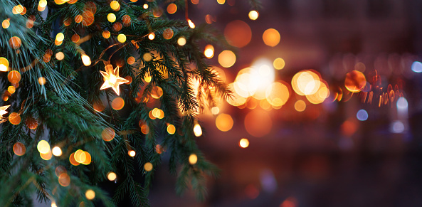 Christmas tree with garland lights. Evening city with blurred background and bright lights