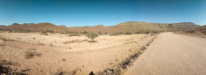 Panorama of a dirt track road approaching mountains in the Namib-Naukluft National Park, Namibia