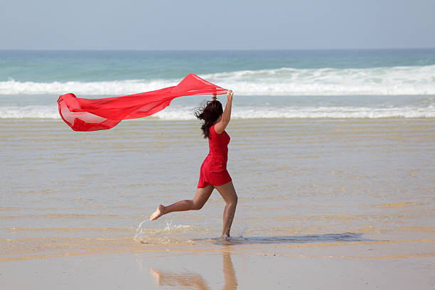 istock Woman running on beach holding red scarf in wind (XXXL) 176158475