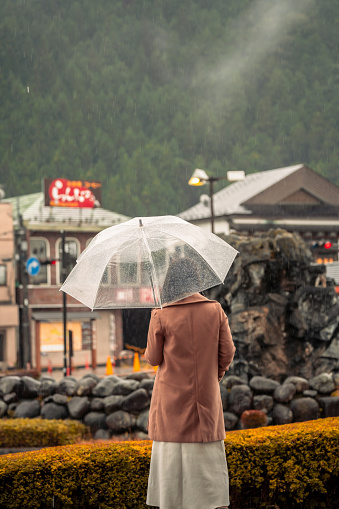 Portrait Asian woman with clear umbrella standing alone on the rain in autumn season.