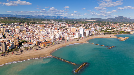 This aerial drone photo shows the coastal town of Vinaros in the province of Castellon in Spain. There is a boulevard at the beach with a lot of apartment buildings.