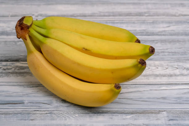 istock Barely ripe yellow bananas on light blue wooden table in the kitchen. 1761596625
