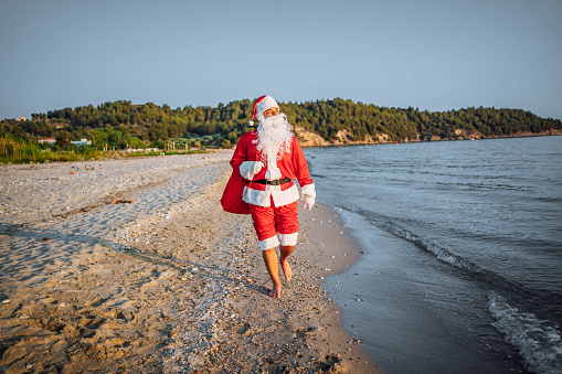 Santa Claus enjoying while walking on the beach during sunset
