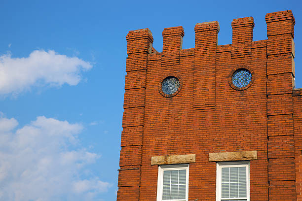 Powerfully bright orange bricks created in Georgia's rich soil jump out in vibrant color with dusk light on this old Gothic brick wall with two Rose Windows with a top looking like a castle battlement