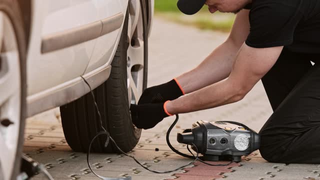 Man Inflates Tire With Portable Pump As Mechanic