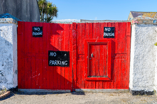 A red wooden gate with three handpainted signs saying 