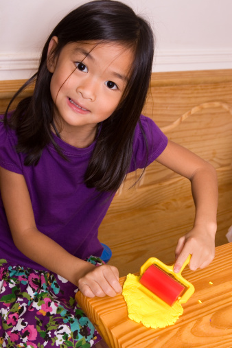 Chinese little girl using roller on her playdoh (shallow dof)