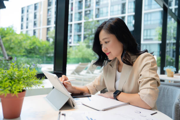 istock Attractive young Asian woman smiling thinking, planning, writing in notebook on tablet 1761638180