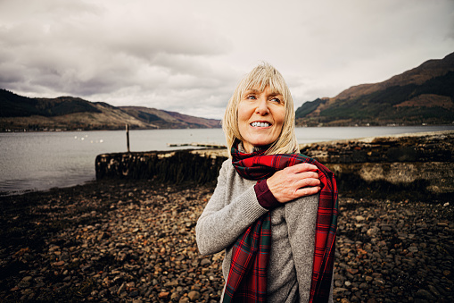 Woman wearing Grant tartan on the shore at Shiel Bridge in the Western Highlands of Scotland.
