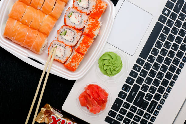 istock Sushi and rolls with chopsticks and laptop on a black background 1761640565