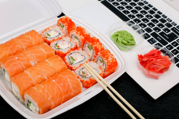 istock Sushi rolls in a lunch box with chopsticks and laptop on black background 1761640573