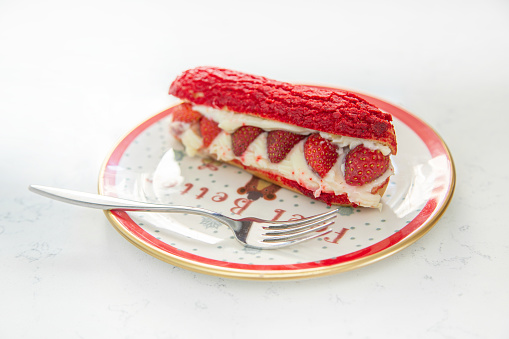 Fresh cake with strawberries on a red plate with a cup of cappuccino. Food and Christmas mood on a white background