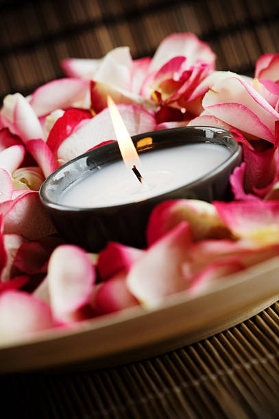 Scented candle burning on a round wooden carved board indoors