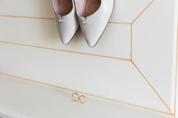 istock White bridal shoes on a patterned surface with gleaming wedding rings in focus. High angle view evoking wedding day emotions. 1761647238