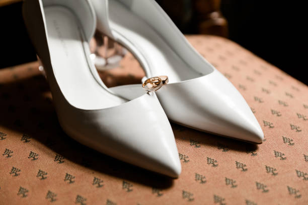 istock White heels with a golden ring atop, on patterned fabric. Close-up with a soft-focus background, evoking romance and elegance. 1761648388
