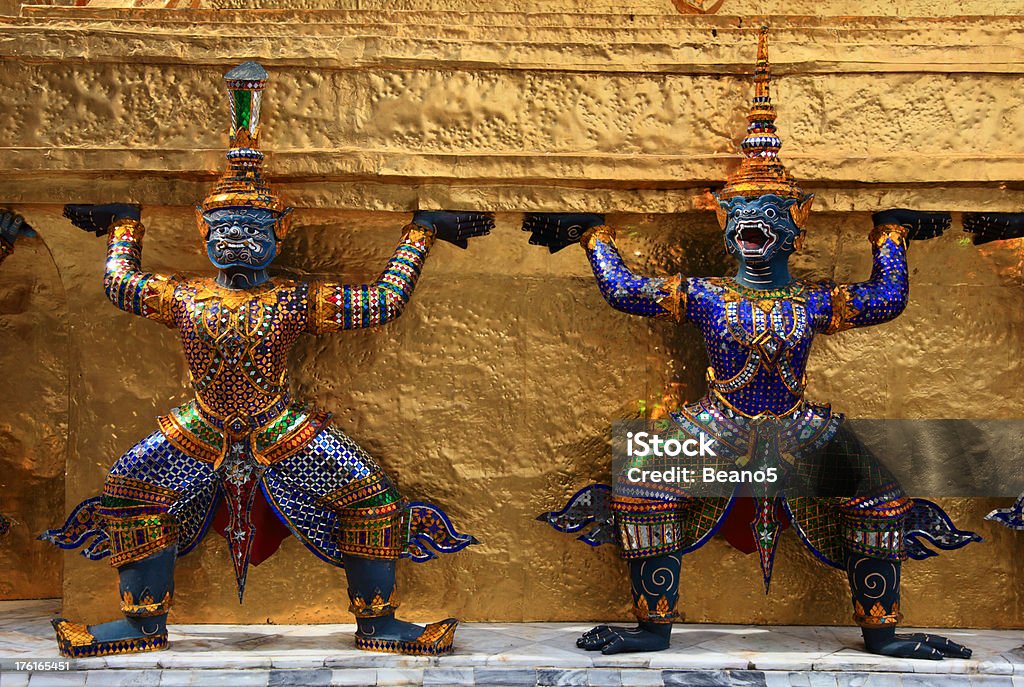 Guards "Guards holding up Chedi statue outside the Emerald Buddha Temple, Grand Palace, Bangkok, Thailand." Bangkok Stock Photo