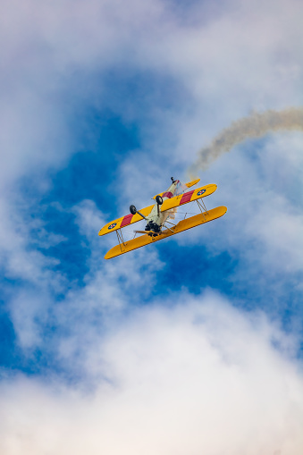 Leszno, Poland - June 17 2023: Antidotum Airshow Leszno 2023 and acrobatic shows of yellow Boeing Stearman plane on a blue clouy sky