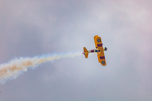 Leszno, Poland - June 17 2023: Antidotum Airshow Leszno 2023 and acrobatic shows of yellow Boeing Stearman plane on a blue clouy sky