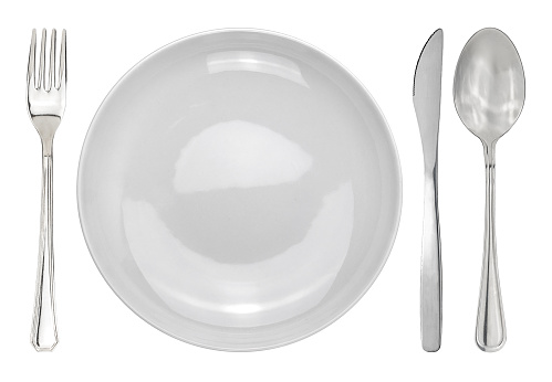 Table setting with a white plate next to cutleries. Plate with fork and knife and spoon isolated on white with clipping path included