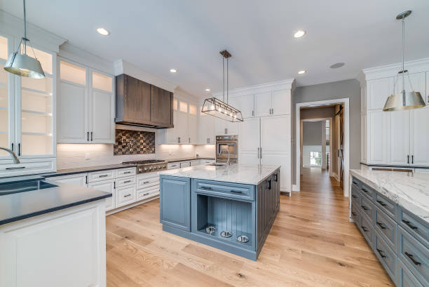 Large kitchen with island surrounded by white quartzite countertops Natural engineered wood flooring with a perfect place to feed the dog inside the kitchen island cabinet stock pictures, royalty-free photos & images