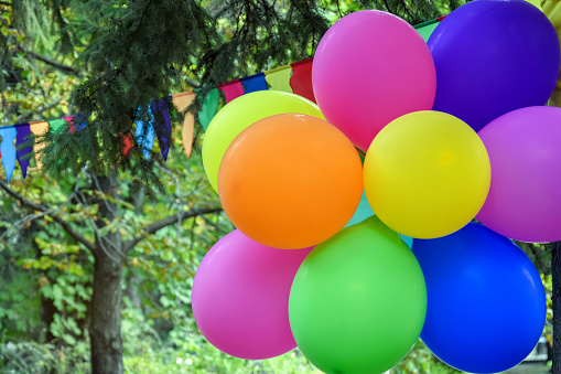 Colorful balloons and multicolored triangular flags on background of autumn foliage in city Park. Close-up. Selective focus.