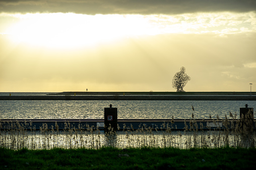 26.03.2023, Lelystad, Netherlands,  Antony Gormley's metal statue of a man sitting on his heels, also known as The Shitting Man