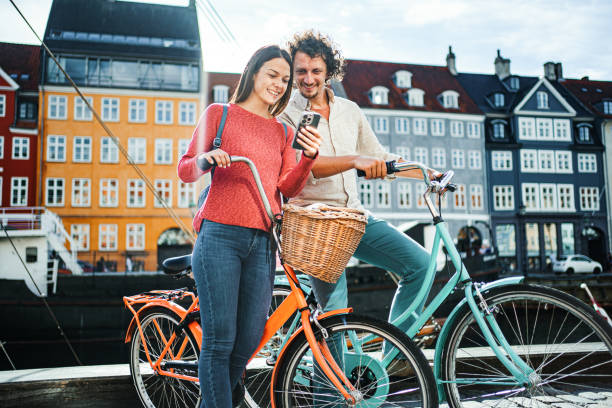 istock Young romantic couple with their bicycles looking at mobile phone while standing by the Stromma Canal in Copenhagen 1761877661