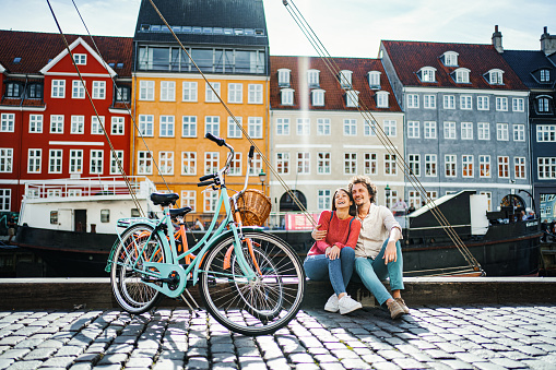 Young romantic couple with their bicycles sitting by the Stromma Canal in Copenhagen
