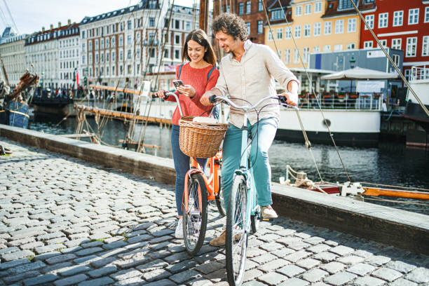 istock Young romantic couple with their bicycles looking at mobile phone while standing by the Stromma Canal in Copenhagen 1761878851