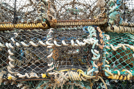 Close-up of large fishing nets and lobster pots seen in an English harbour. The pots are located on a Suffolk beach prior to being loaded on a trawler.