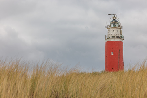 Texel Lighthouse in Netherlands from the beach through the tall grass with a dramatic sky in the background