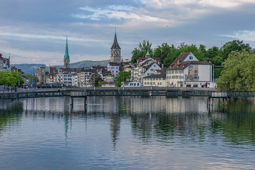 Grossmunster, bridge and buildings in Zurich are reflected in the Limmat River at sunrise