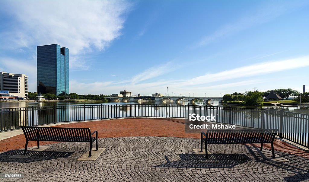 City Skyline A panoramic view of downtown Toledo Ohio's skyline from across the Maumee river at a popular restaurant area with a paver brick boardwalk and a decorative iron railing and park benches to enjoy the view.  A beautiful  blue sky with white clouds for a backdrop. Ohio Stock Photo