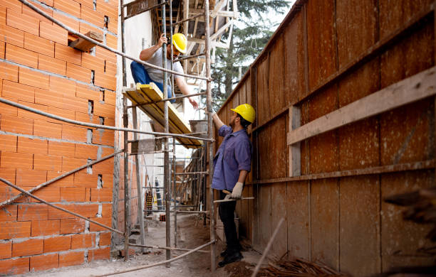 Latin American team of builders working at a construction site using scaffolding - architecture concepts