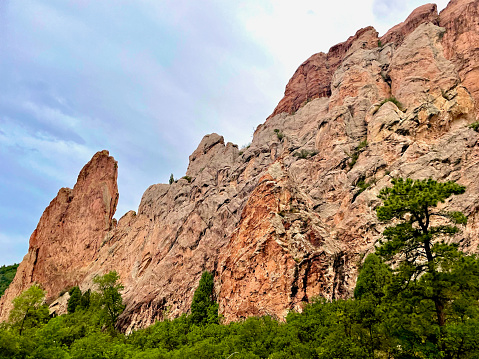 Red rock formations stand out above pine trees within Garden of the Gods Park, a popular public park in the City of Colorado Springs, Colorado.