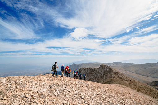 Alpinist climber team is on expedition for couple nights on the mountain,  they are walking in a row.