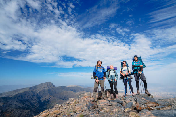 el equipo de alpinistas está mirando a la cámara mirando de pie en la cima de una montaña. - group of people journey effort travel destinations fotografías e imágenes de stock