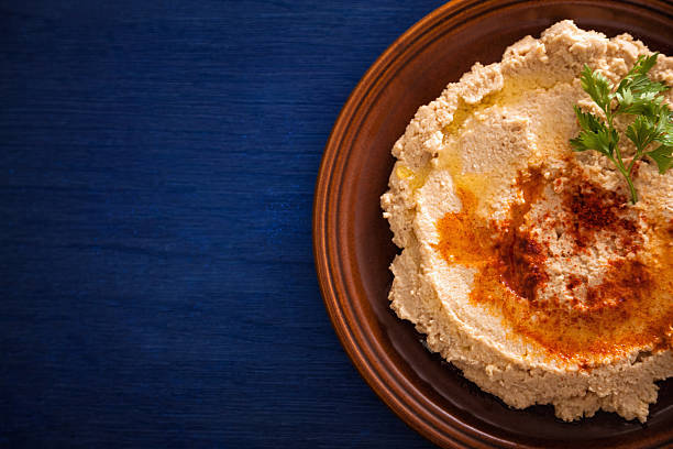 istock Fresh hummus with cilantro in brown bowl on blue table 176204127