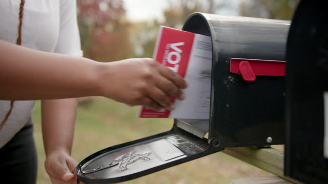 Slow motion lockdown shot of a Black woman receiving a mail-in ballot to vote in the USA Presidential, Senatorial, Congressional, or local election