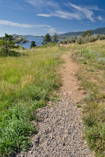 A path leads to a picnic table at the beautiful Horsetooth Reservoir outside of Fort Collins, Colorado. Selective focus on path in foreground.